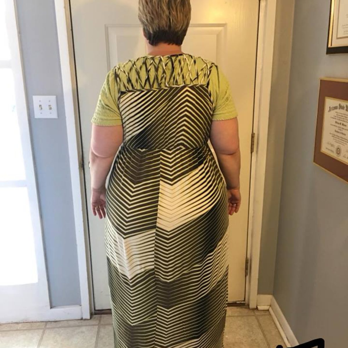 A woman standing in front of a door wearing a dress.