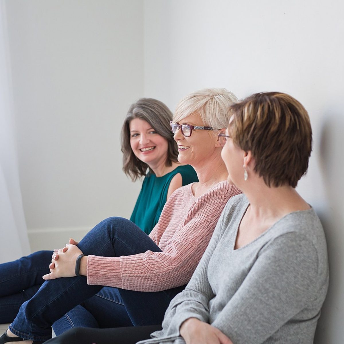 Three women sitting on the floor in front of a window, forming an accountable trio.