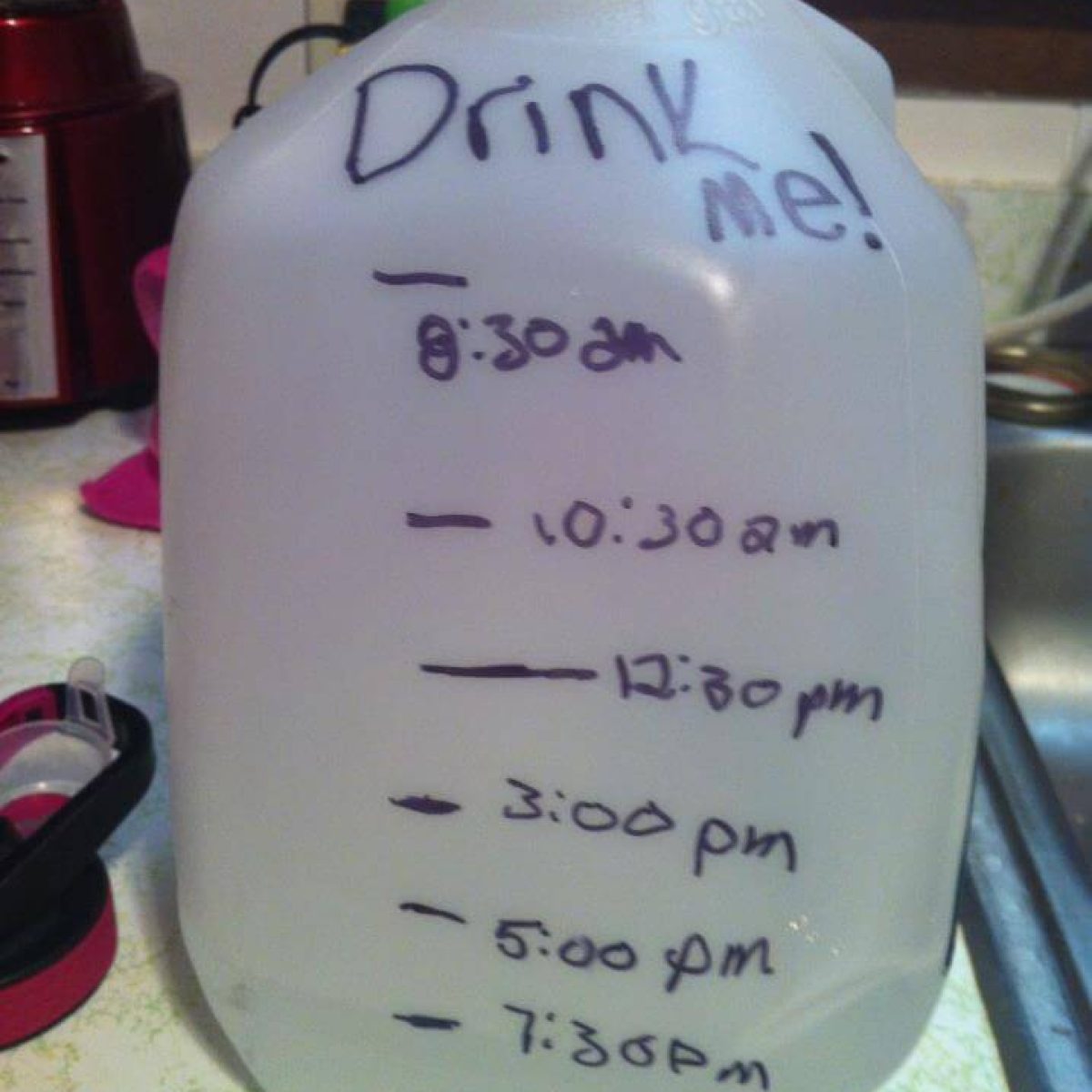 A jug of water with writing on it that says drink me.